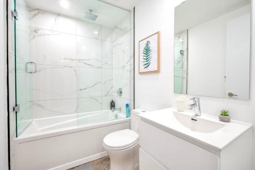 uma casa de banho branca com uma banheira, um WC e um lavatório. em Stylish 2BR Condo in Proximity to City Center em Toronto