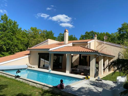un homme assis devant une maison avec piscine dans l'établissement LA VILLA DIANE, Maison d'hôtes, Bed and Breakfast, à Montauban