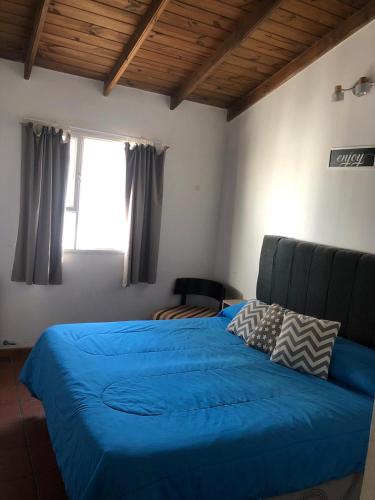 a bedroom with a blue bed and a window at Mamama’s House in Puerto Madryn
