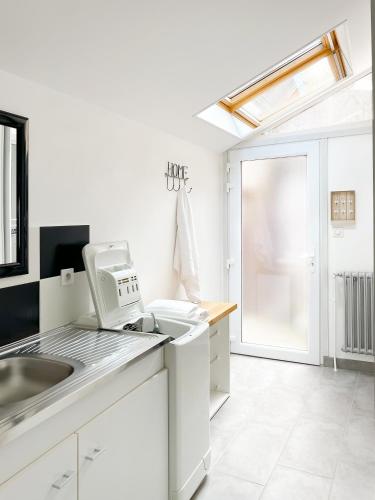 une cuisine avec des armoires blanches, un évier et une fenêtre dans l'établissement Gîte St Ylé, à Pontorson