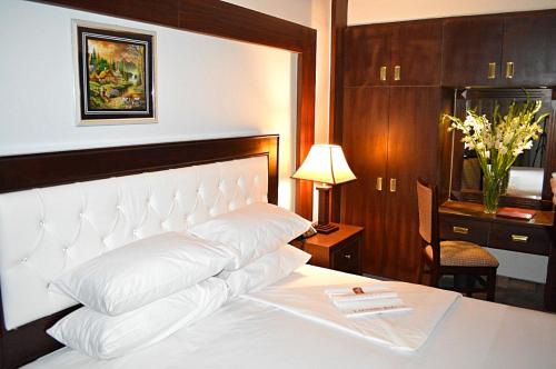 a bedroom with a large white bed with a desk and a lamp at Fort Continental Hotel in Peshawar