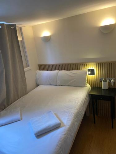 a bed with white sheets and pillows in a room at Exhibition Court Hotel 4 in London