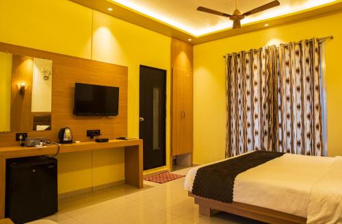 a bedroom with a bed and a desk and a television at Relax Adventure Resort in Igatpuri