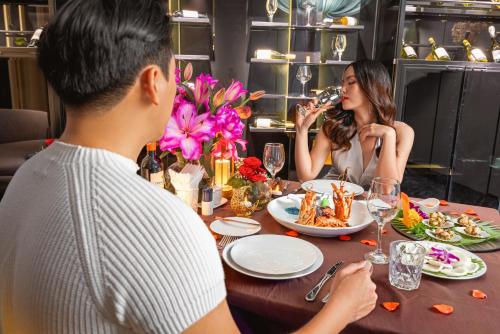 頭頓的住宿－Premier Pearl Hotel Vung Tau，坐在餐桌旁吃食物的男人和女人