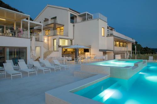 a villa with a swimming pool in front of a house at Zlatni Zalaz,Apartments,Supetarska Draga in Supetarska Draga