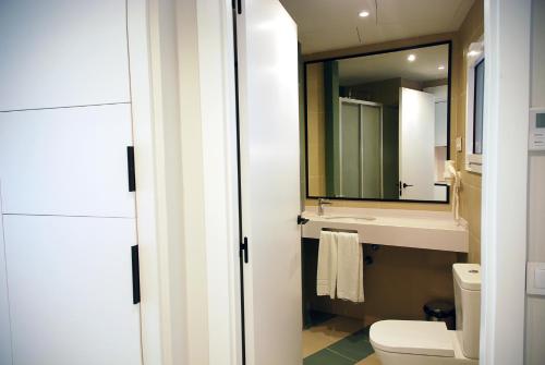 a bathroom with a toilet and a sink and a mirror at Apartamentos Sunway Atlanta in Sitges