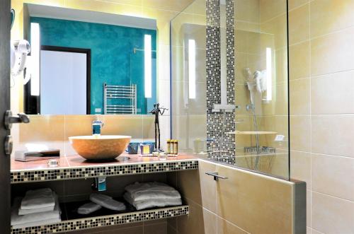 y baño con lavabo y espejo. en Hôtel Liberata & Spa en LʼÎle-Rousse