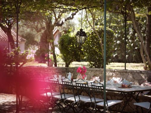 Almeira 4acre Estate, for Unparalleled Seclusion, By ThinkVilla في مدينة زاكينثوس: طاولة مع كراسي ومصباح في حديقة