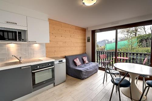 une cuisine avec une table et un canapé et une table dans l'établissement Pré Fleuri 1 - Appt vue lac et montagne, à Gérardmer