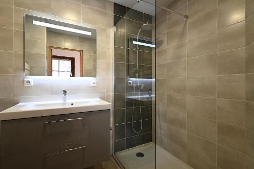 une salle de bain avec un lavabo et une douche avec un miroir dans l'établissement Pré Fleuri 1 - Appt vue lac et montagne, à Gérardmer