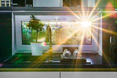 a kitchen sink with a sun shining through a window at Willa z jacuzzi na polu golfowym Sierra Golf Homessimo Stars in Gowino