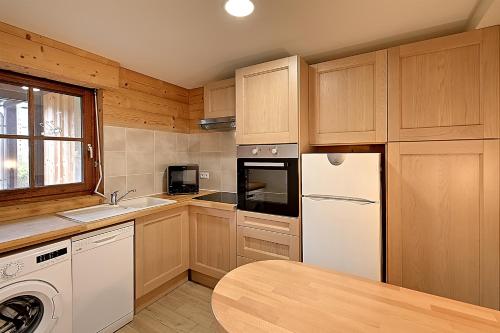 une cuisine avec des armoires en bois et un réfrigérateur blanc dans l'établissement Pré Fleuri 2 - Vue Lac et Montagne, à 600m du lac, à Gérardmer