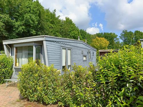 una pequeña casa gris en medio de unos arbustos en Vakantiehuisje Veluwe bij Speuldersbos, en Putten