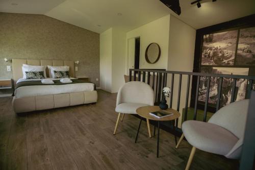 a bedroom with a bed and two chairs and a table at Casa da Adega in Vila Nova de Foz Coa