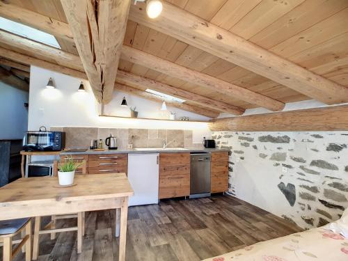Il comprend une cuisine dotée de plafonds en bois et d'une table en bois. dans l'établissement calme et vue, à Montvalezan