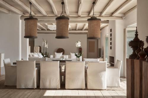a dining room with white chairs and a table at Greece Dream Holidays Villas 2 in Agios Sostis Mykonos