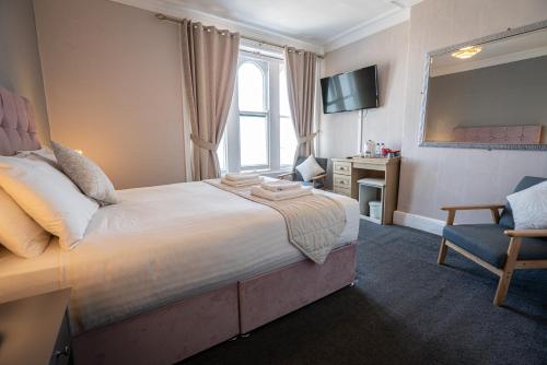 a bedroom with a bed and a chair and a television at The Central Hotel in Llandudno