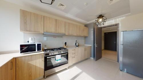 a kitchen with wooden cabinets and a stove and a microwave at Unlock Metropolis Business Bay in Dubai