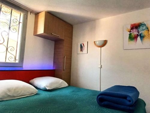 - une chambre avec un lit et une fenêtre avec une lumière bleue dans l'établissement Appartement T2 climatisé avec mezzanine, piscine et parking, proche plage - Agde - FR-1-607-119, au Cap d'Agde