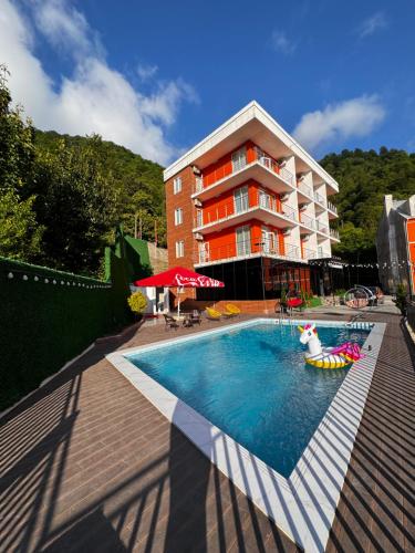 un hotel con piscina frente a un edificio en Orange Villa Kvariati en Kvariati
