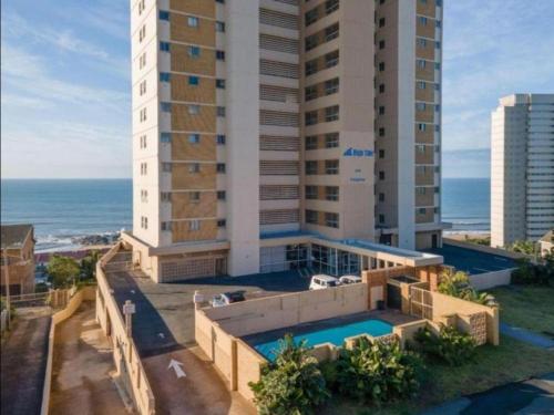 a building with a swimming pool next to the ocean at High Tide Beach Condo in Durban