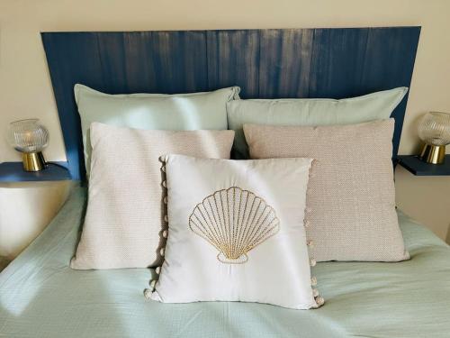 a bed with a pillow with a shell on it at L'Escapade marine appartement avec jacuzzi privé in Cayeux-sur-Mer