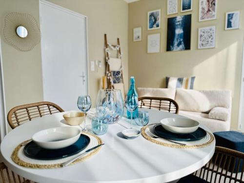 - une table blanche avec des assiettes et des verres à vin dans l'établissement L'Escapade marine appartement avec jacuzzi privé, à Cayeux-sur-Mer
