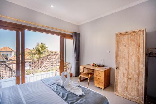 a bedroom with a bed and a desk and a window at Kubu Gena Guesthouse Canggu in Canggu