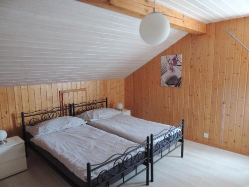 Schlafzimmer mit einem schwarzen Bett und Holzwänden in der Unterkunft Chambre d'hôte du Moulin in Savièse