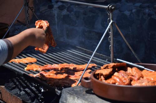 a person is cooking meat on a grill at La Casa de Mamayacchi in Coporaque