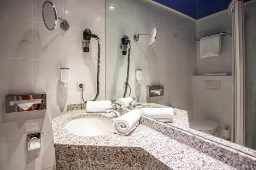 a bathroom with a sink and a shower at Koener Hotel & Spa in Clervaux