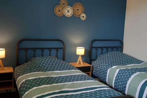 - 2 lits dans une chambre aux murs bleus et 2 lampes dans l'établissement Appartement 3 pièces avec parking et balcon - Le Havre, au Havre