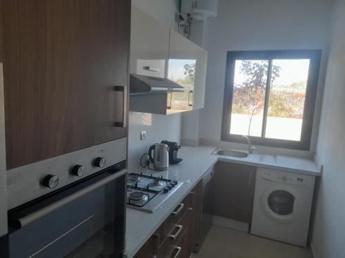 una cocina con estufa horno superior al lado de una ventana en Vacances Soleil Piscine & Plage Bouznika, en Bouznika