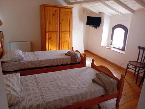 um quarto com duas camas e uma televisão na parede em Su Mulinu 
