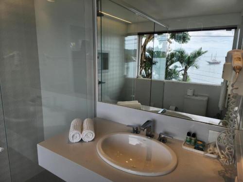 baño con lavabo y espejo grande en Byblos Pousada, en Búzios