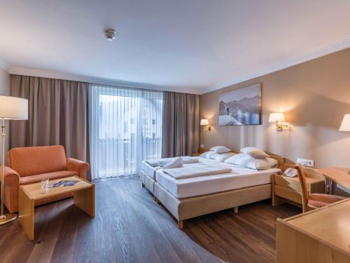 una habitación de hotel con una cama grande y una silla en SCOL Sporthotel Zillertal en Fügen