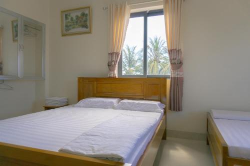 um quarto com uma cama grande e uma janela em Khách Sạn An Bình Đảo Phú Quý em Phú Quý