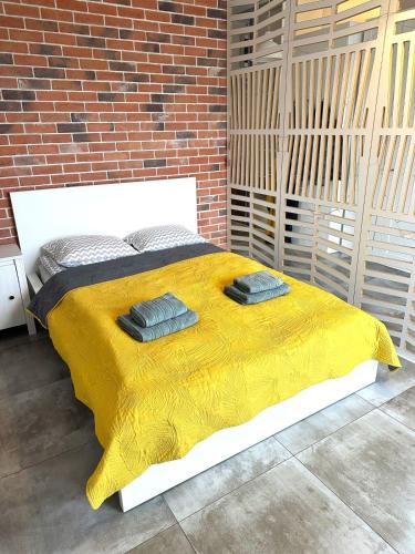 a bed with a yellow blanket and a brick wall at Apartament Łodzianka in Łódź