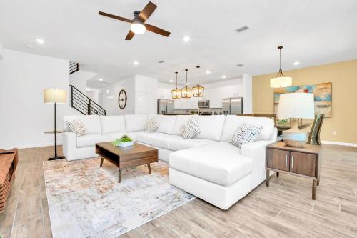 a living room with a white couch and a table at Upstay 9BR Disney Retreat w Pool, BBQ & Hot Tub in Kissimmee