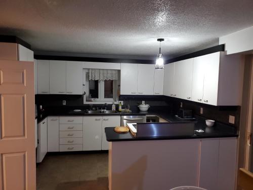 eine Küche mit weißen Schränken und einer schwarzen Arbeitsplatte in der Unterkunft Private Room 5 with Free WIFI and Parking in Edmundston