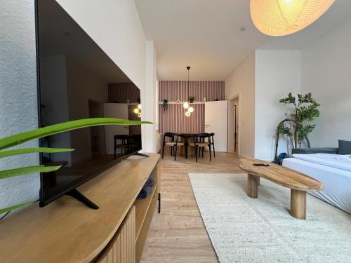 uma sala de estar com uma televisão grande e um quarto em FLATLIGHT - Stylish apartment - Kitchen - Parking - Netflix em Hildesheim