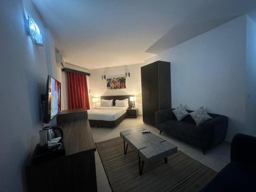 - un salon avec un canapé et un lit dans une chambre dans l'établissement Hotel Belle Vie, à Kinshasa