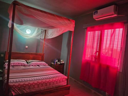 a bedroom with a bed with red curtains and a window at Villa Duchesse in Sali Nianiaral