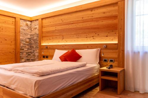 a bedroom with a bed with a wooden wall at Alpen Garten Hotel Margherita in Rumo