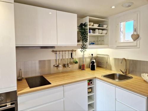 a kitchen with white cabinets and a sink at Les Embruns / F2 Hyper centre Houlgate in Houlgate
