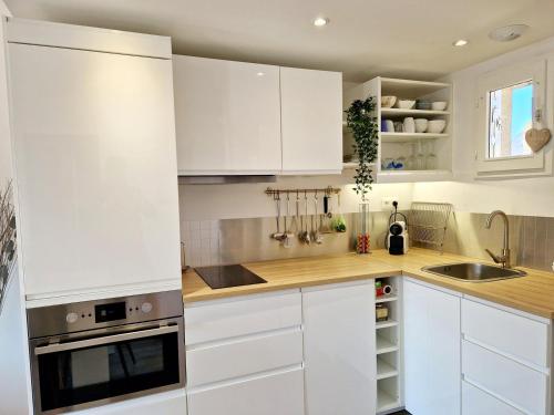 a white kitchen with white cabinets and a sink at Les Embruns / F2 Hyper centre Houlgate in Houlgate