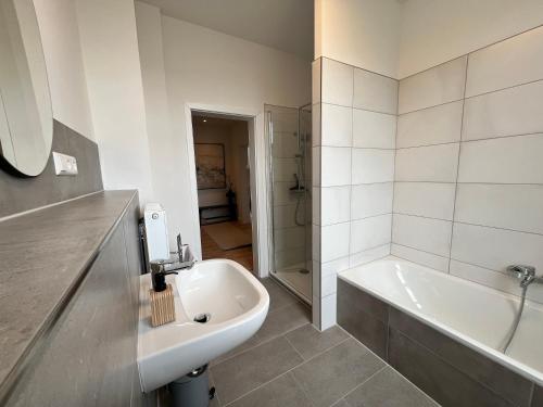 a bathroom with a tub and a sink and a bath tub at FLATLIGHT - Stylish apartment - Kitchen - Parking - Netflix in Hildesheim