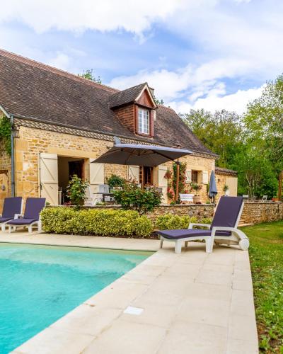 une maison avec une piscine et deux chaises longues dans l'établissement La Bergerie, à Mauzac-et-Grand-Castang