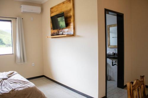 a room with a bed and a mirror and a sink at Hotel Águas Lindas in Itamonte