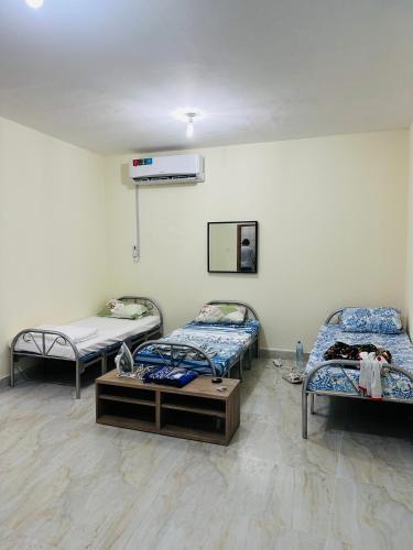 um quarto com três camas e uma mesa em AM a shared room em Doha